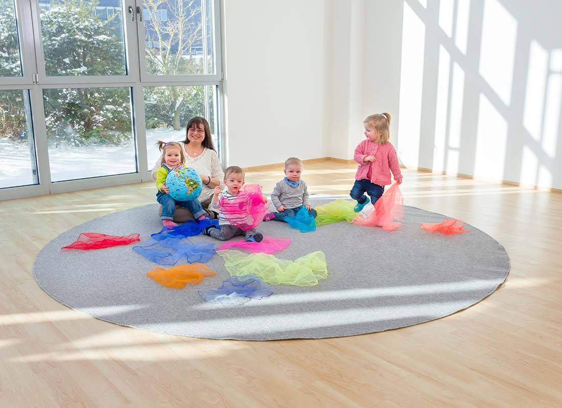 Betzold Kurzflor Teppich in grau mit Erzieherin und Kindern und bunten Tüchern