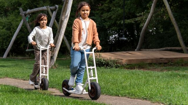 Zwei Mädchen auf Rollern im Park