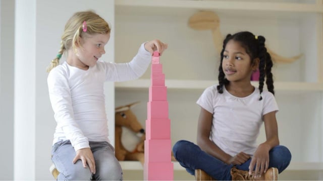 zwei Kinder sitzen am Boden und stapeln die Würfel des Rosa Turms