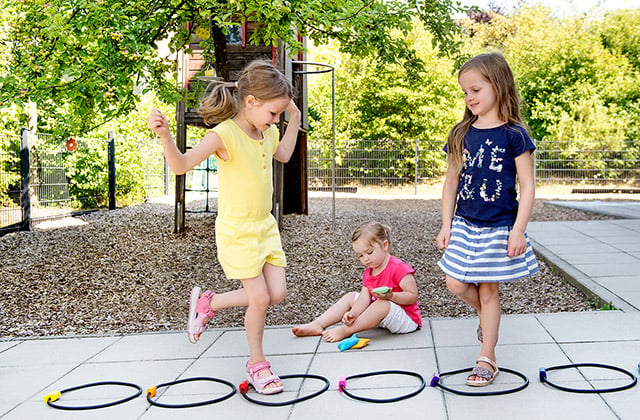 Motorik & Bewegung Kinder spielen Hüpfspiel im Garten